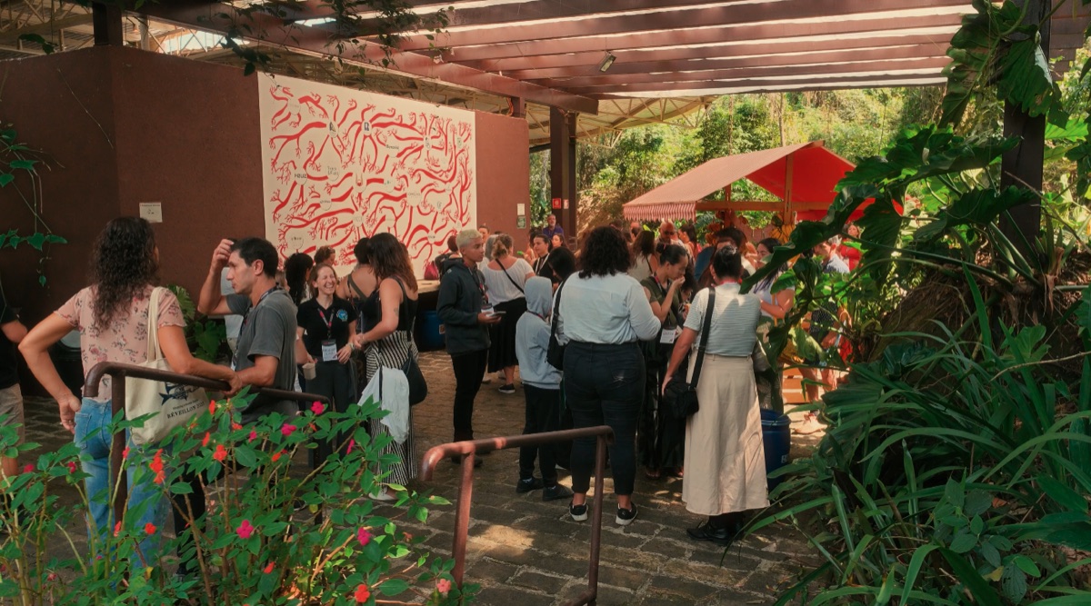 Participantes no intervalo do TEDx, painel artístico vermelho de raízes